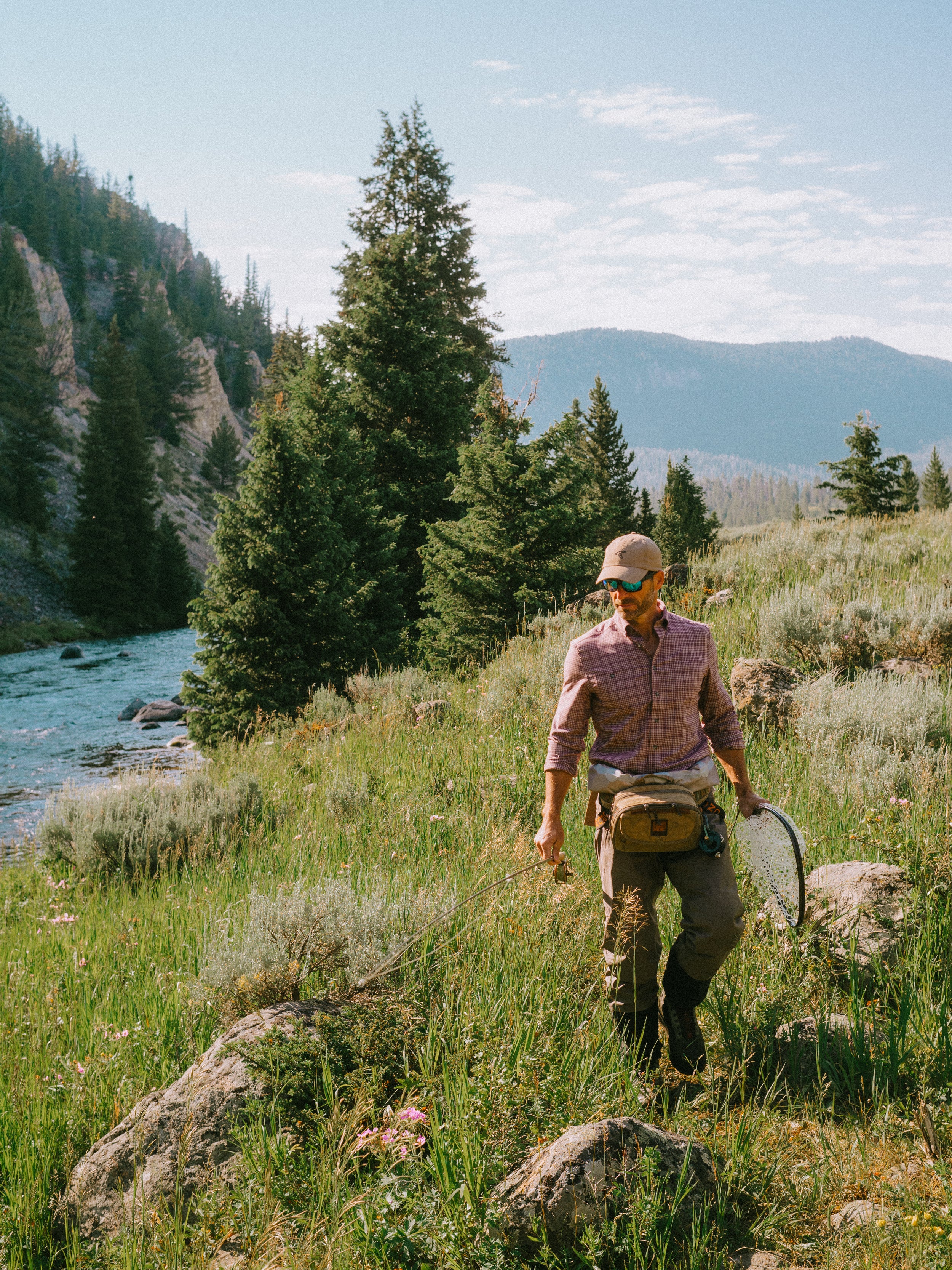 Man standing outside with a fly fishing rod in GenTeal clothing